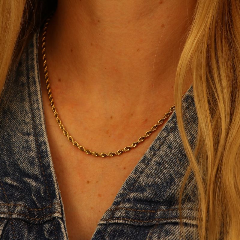Gold chain necklace worn by a person with denim jacket