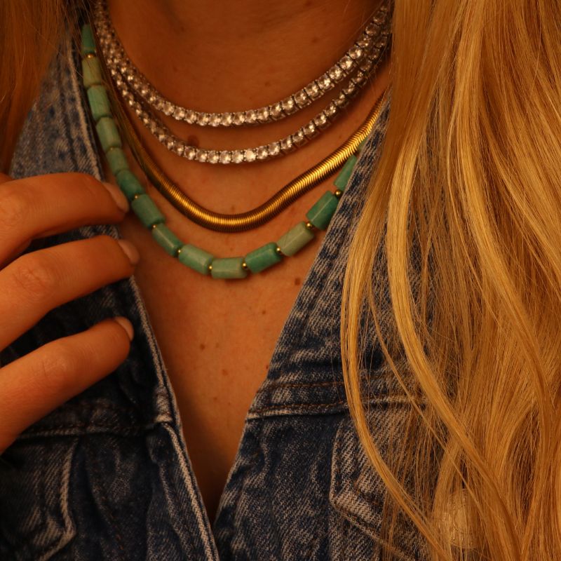 Close-up of a person wearing multiple necklaces with a denim jacket.